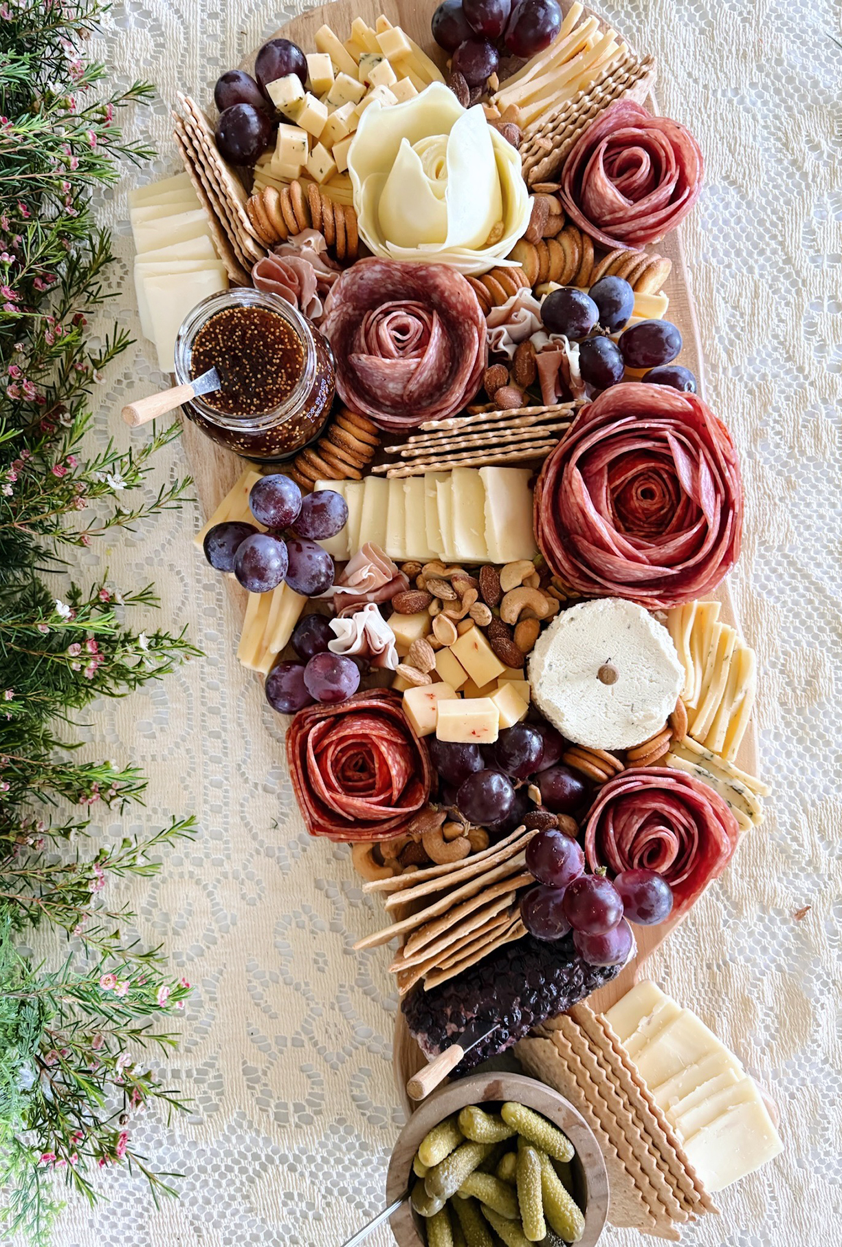 charcuterie board with meat roses and assorted cheese, nuts, grapes and crackers on board